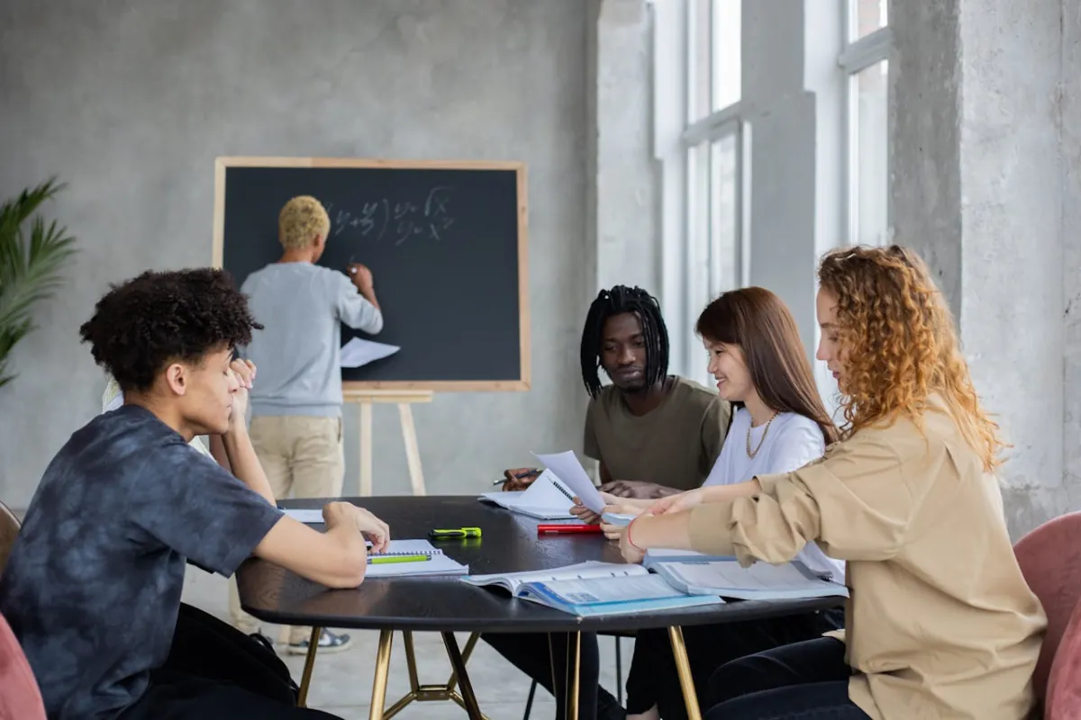 Diverse group of international students learning mathematics from an experienced tutor writing equations on a board